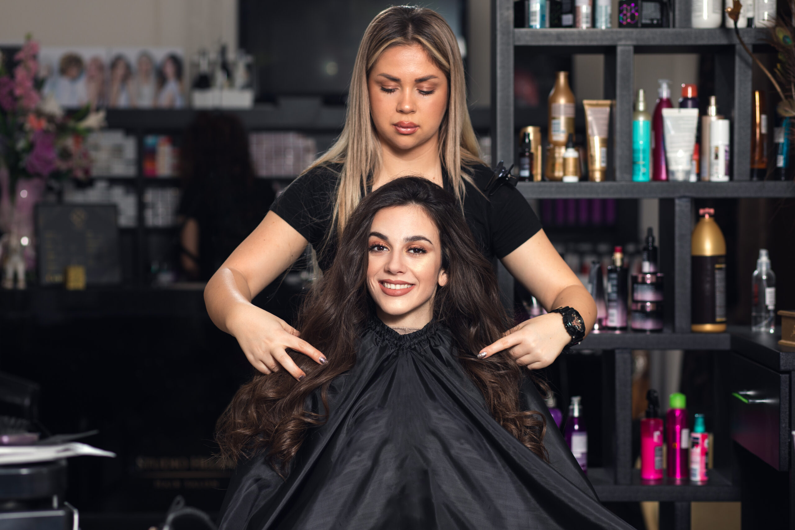 Hairdresser styling a smiling young woman's hair