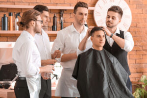 Professional barber teaching young men how to cut hair in salon
